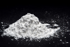Mound of fine white drug or poison like powder substance scattered over black (it's confection sugar!)